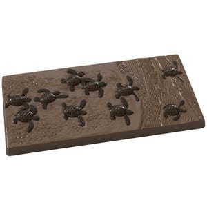 May include: A rectangular, brown decorative piece featuring raised relief images of sea turtles. The turtles are scattered across a textured surface, with some appearing to be moving towards a raised, textured area resembling a shoreline. The overall design evokes a beach scene.