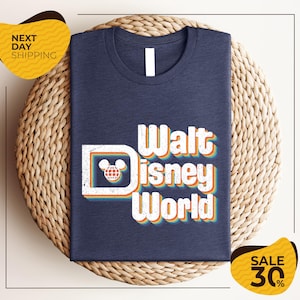 A navy blue t-shirt with the text "Walt Disney World" printed on it, along with a Mickey Mouse logo, is displayed on a woven basket. The image also includes text indicating a sale with a 30% discount.