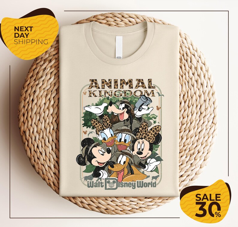 a t-shirt with a Disney-themed graphic design, including Mickey Mouse, Minnie Mouse, Donald Duck, and Goofy. The t-shirt is displayed on a woven basket, and there are two yellow sale signs indicating a 30% discount.