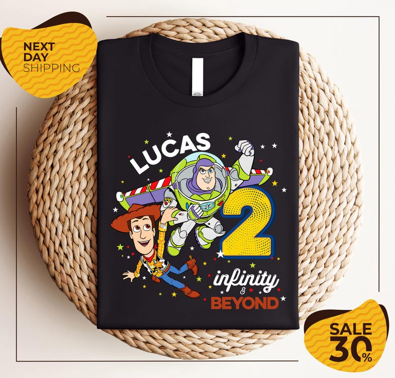 A black t-shirt with a colorful graphic design featuring characters from the Toy Story franchise, including Buzz Lightyear and Woody, along with the text "Lucas 2 infinity & beyond".