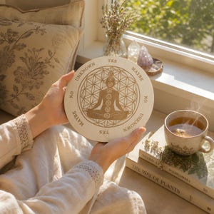 May include: A light wooden meditation guide with a central figure in a lotus position, surrounded by text that reads "Yes", "Maybe", "No", and "Unknown". The design includes a geometric pattern and chakra symbols. A cup of tea and books are in the background.