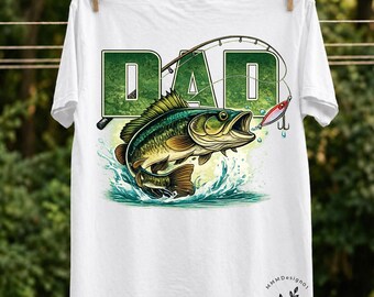 May include: White t-shirt featuring a green and white graphic of the word "DAD" with a fishing rod and a leaping fish. The fish is green, brown, and yellow, with water splashing around it. A red and white lure is near the fish.