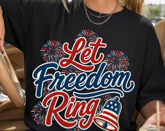 May include: Black t-shirt with a patriotic design. The graphic features the text "Let Freedom Ring" in red and blue script, surrounded by fireworks and a bell with a US flag design. The shirt is a casual style.