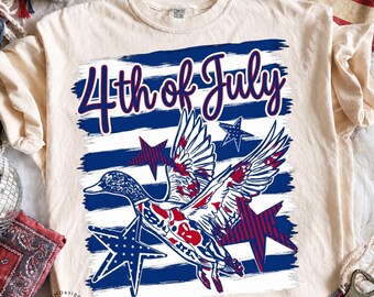 May include: Cream-colored t-shirt featuring a patriotic design for the 4th of July. The graphic includes a duck with red, white, and blue accents, stars, and the text "4th of July" in a script font. The shirt has a crew neck and short sleeves.