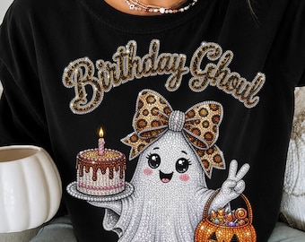 May include: A black sweatshirt featuring a graphic of a white ghost with a leopard print bow, holding a birthday cake with a lit candle and an orange jack-o'-lantern candy bucket. The text "Birthday Ghoul" is printed above in a leopard pattern.