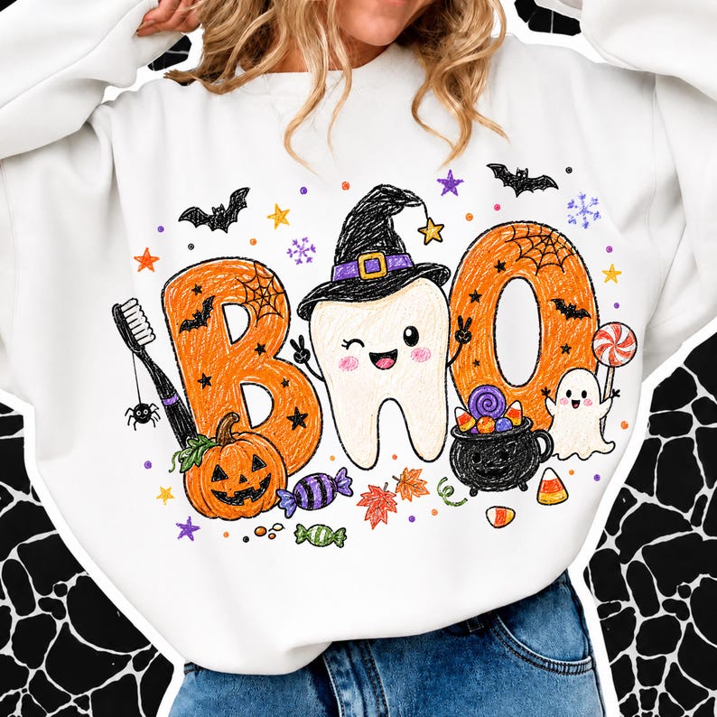 K&ouml;nnte beinhalten: Ein wei&szlig;es Langarm-Sweatshirt mit einer bunten Grafik und dem Schriftzug BOO. Das Design zeigt einen l&auml;chelnden Zahn mit Hexenhut, eine Zahnb&uuml;rste, einen K&uuml;rbis, einen schwarzen Kessel mit S&uuml;&szlig;igkeiten, ein Gespenst, Flederm&auml;use und kleine Sterne.