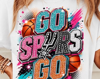 Puede incluir: Camiseta blanca con la frase "GO SPURS GO" en un diseño brillante. El diseño incluye balones de baloncesto y un logotipo del equipo, con detalles turquesa, rosa, naranja y negro.