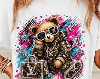 May include: A white t-shirt featuring a graphic of a brown teddy bear wearing sunglasses and a brown patterned hoodie. The bear is sitting next to a matching brown patterned handbag. The design includes pink and blue paint splatters and stars.