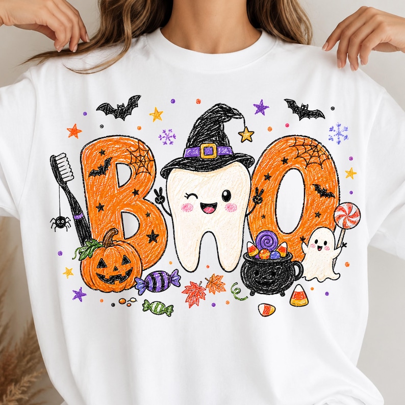 K&ouml;nnte beinhalten: Ein wei&szlig;es Sweatshirt mit Rundhalsausschnitt und einer bunten Grafik im Buntstift-Stil mit dem Text "BOO". Das Design zeigt einen zwinkernden Zahn mit Hexenhut, einen orangefarbenen K&uuml;rbis, einen schwarzen Kessel, ein Gespenst, eine Zahnb&uuml;rste und S&uuml;&szlig;igkeiten.