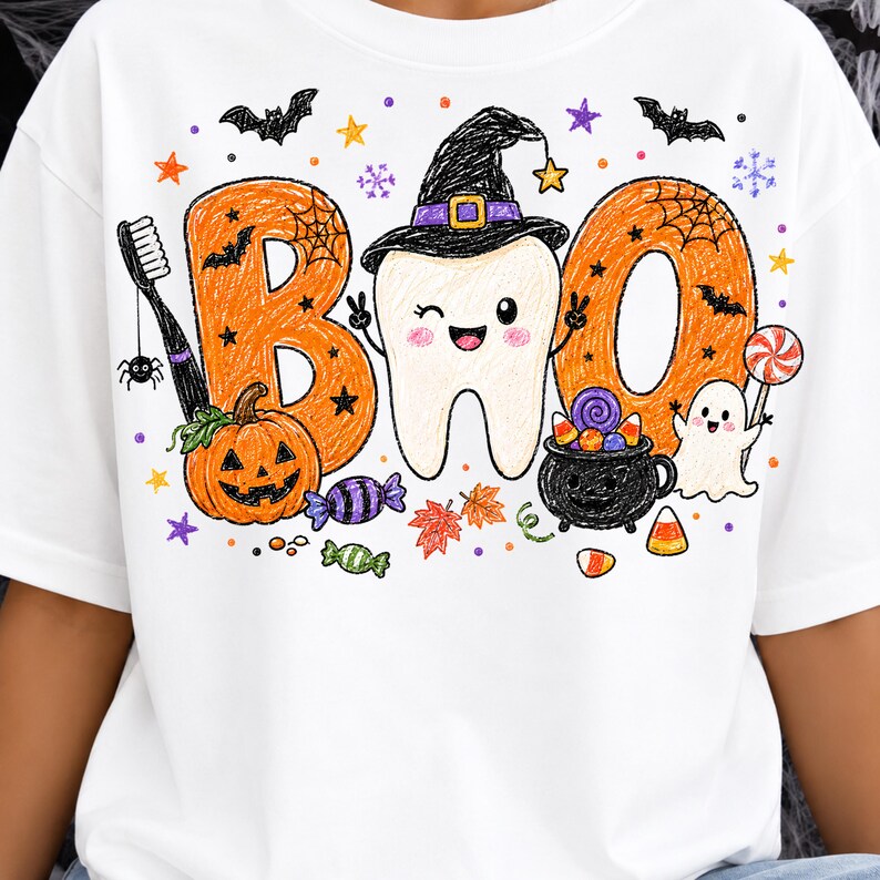 K&ouml;nnte beinhalten: Ein wei&szlig;es T-Shirt mit einer bunten Grafik und dem Schriftzug BOO, wobei der Buchstabe B orange ist, der Buchstabe O ein zwinkernder Zahn mit schwarzem Hexenhut ist und das zweite O orange ist. Enth&auml;lt eine Zahnb&uuml;rste, K&uuml;rbis, Geist und S&uuml;&szlig;igkeiten.