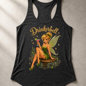 May include: A charcoal gray racerback tank top featuring a graphic illustration of a fairy with blonde hair in a bun, wearing a green dress and shoes, holding a pink cocktail with a lime slice. The text Drinkerbell is printed in gold above.
