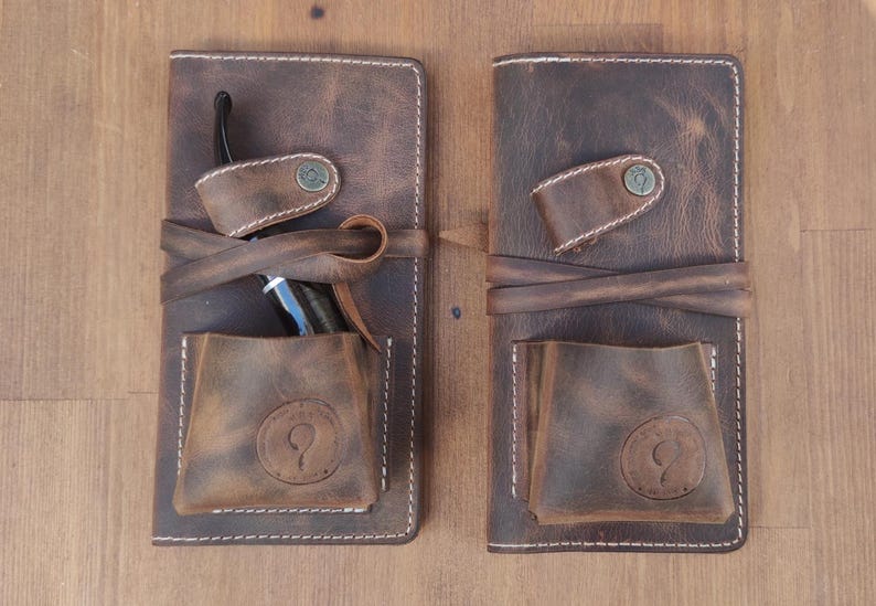 May include: Two brown leather pouches with white stitching. Each pouch has a flap with a snap closure and a small pocket on the front. One pouch has a pipe inside.
