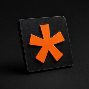 Puede incluir: Una placa cuadrada negra con un símbolo de asterisco naranja brillante en relieve centrado en su superficie. La placa tiene un acabado texturizado y un diseño geométrico limpio con esquinas redondeadas, creando un fuerte contraste.