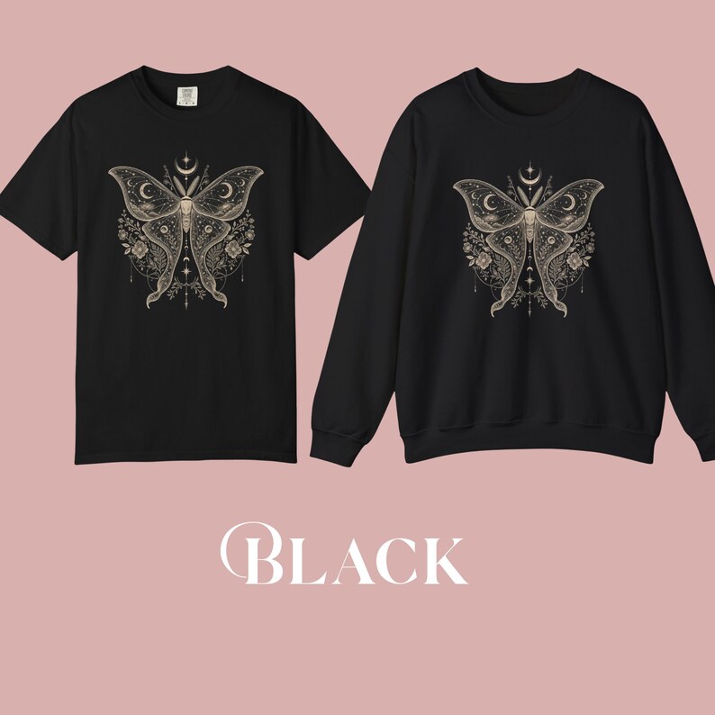 A black short-sleeved t-shirt and a black crewneck sweatshirt, both featuring a gold celestial moth design, are displayed side-by-side.