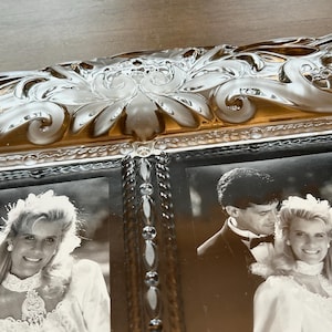 May include: A rectangular glass picture frame featuring a decorative, molded border with an amber-tinted, scrollwork design. The frame holds two black and white photographs of a couple in formal wedding attire, separated by a vertical row of clear, faceted glass beads.