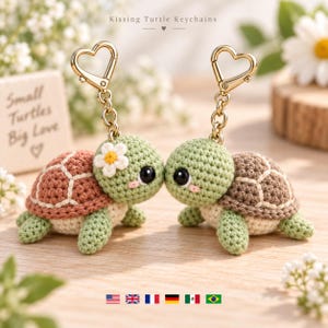 Puede incluir: Dos llaveros de tortuga tejidos a ganchillo con cierres dorados en forma de corazón. Las tortugas tienen cabezas verde claro, vientres color crema y caparazones marrones con costuras blancas. Una tortuga tiene una flor blanca. Texto: Kissing Turtle Keychains.