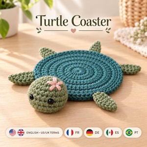 May include: A round, dark teal crocheted coaster shaped like a turtle. The turtle has a light green head with two black bead eyes and a small pink flower detail. It features four light green flippers extending from the circular body.