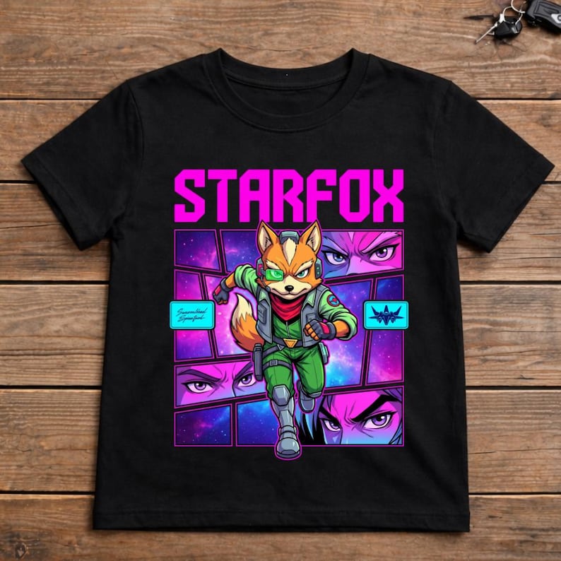 May include: A black short-sleeved t-shirt featuring a graphic print of a fox character in a green flight suit with the text STARFOX in bright pink. The design includes a cosmic purple background, segmented comic-style panels, and close-up eye details.
