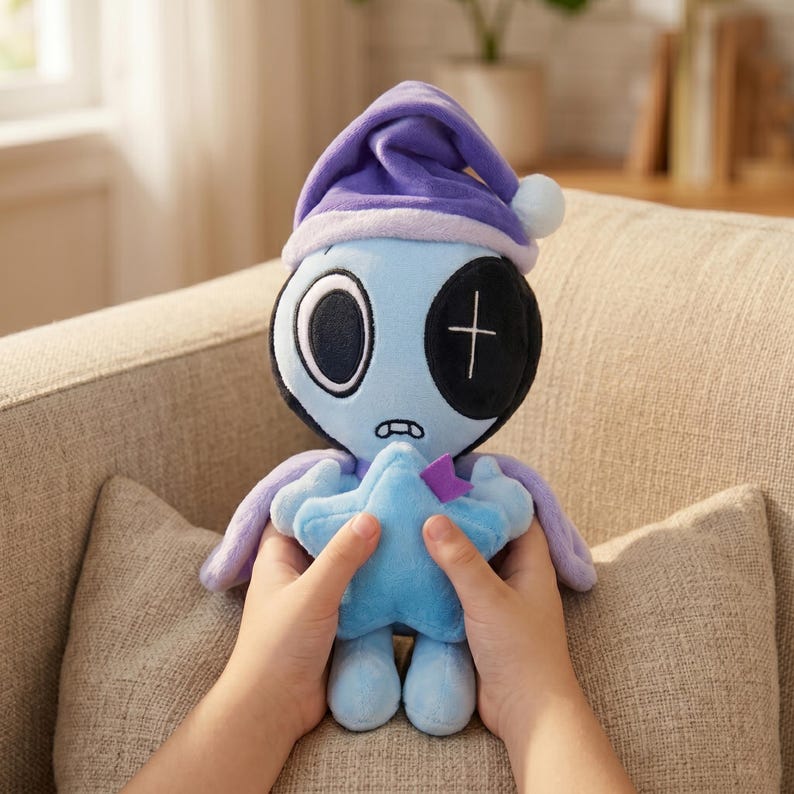 May include: A blue plush doll with a purple nightcap and star-shaped hands. The doll has one large black eye with a white cross and a smaller white eye. It is held in front of a neutral-colored background.