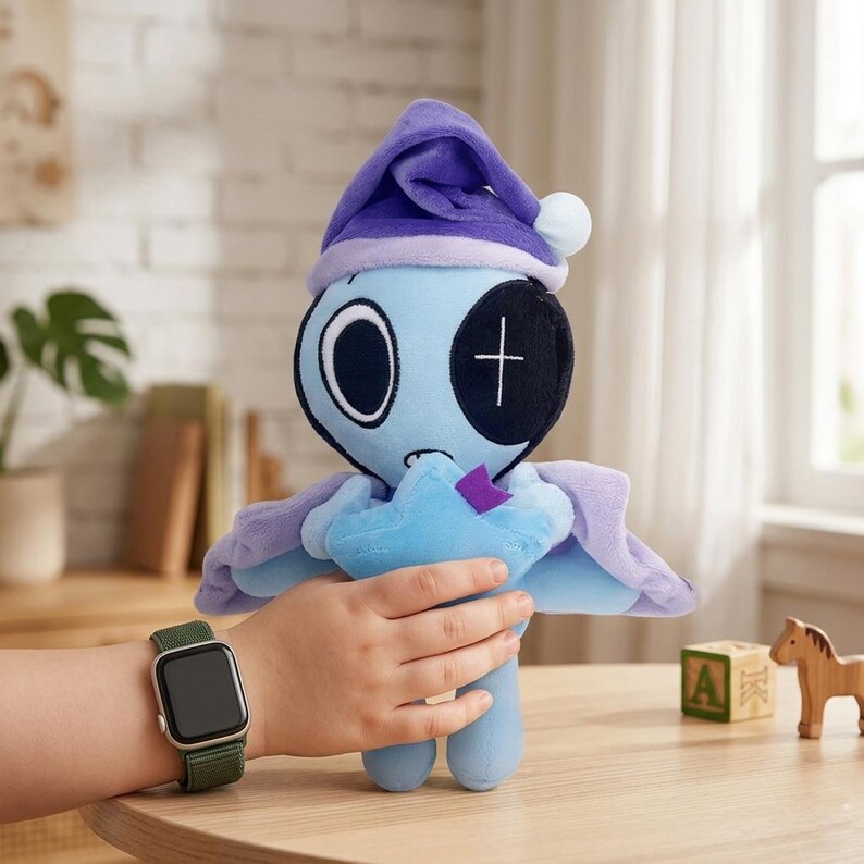 May include: A plush toy in the shape of a blue creature with a purple nightcap and cape. The toy has large eyes, a stitched cross on one eye, and a star-shaped object in its hands. The toy is being held by a child.