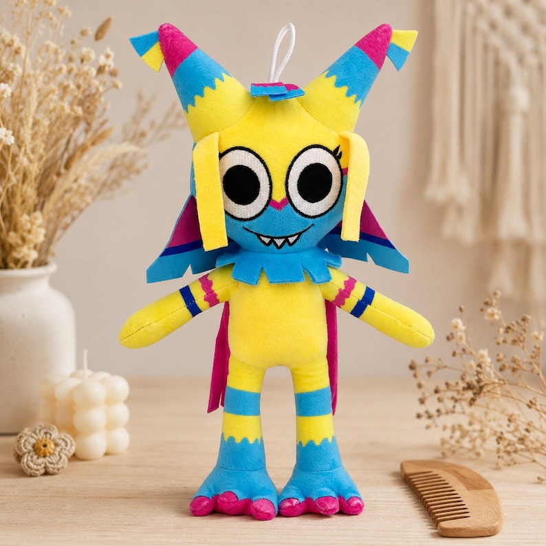 Pu&ograve; includere: Un peluche a forma di personaggio dei cartoni animati con grandi occhi, viso blu e corpo giallo. Il giocattolo ha accenti blu e rosa, anche sulle orecchie, sulle braccia e sulle gambe. Ha un cordino bianco per appenderlo.