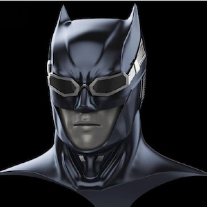 May include: A dark blue, smooth-textured cowl mask featuring pointed ears and integrated silver-rimmed goggles with dark lenses. The mask covers the head and neck, revealing a neutral-toned face with a defined nose, mouth, and chin area.