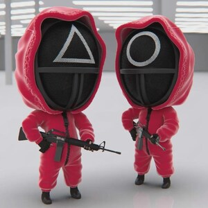 May include: Two stylized figures wearing bright red hooded jumpsuits and black masks. One mask features a white triangle symbol, and the other features a white circle symbol. Each figure holds a black toy rifle, standing in a uniform pose.