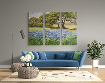 May include: A blue velvet sofa with green throw pillows sits in front of a wall with a three-panel canvas print of a field of bluebonnet flowers.