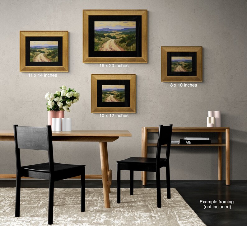 May include: Four framed landscape paintings with gold frames of varying sizes: 20.3 x 25.4 cm, 25.4 x 30.5 cm, 27.9 x 35.6 cm, and 40.6 x 50.8 cm. The paintings depict a dirt road winding through a valley with green hills and a blue sky. The paintings are displayed on a gray wall.
