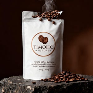 May include: A white packet of Timoho Coffee Sumatra Mandheling Arabica single origin roasted beans. The packet features a circular logo with two coffee beans and the brand name. Coffee beans are scattered around the packet and on a spoon.