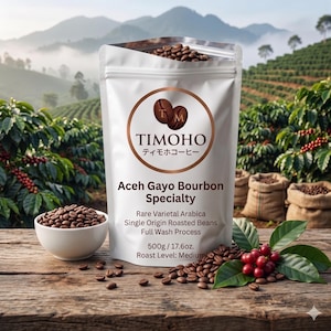 May include: A white bag of TIMOHO Aceh Gayo Bourbon Specialty coffee beans, with the brand logo and Japanese text. The bag is open, revealing the beans. A small white bowl of beans and scattered beans are in front of the bag. The bag contains 500g / 17.6oz of coffee.