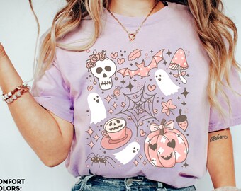 May include: A purple t-shirt with a cute Halloween design featuring a skull, ghosts, bats, a pumpkin, and a spider. The design is in pink, white, and black.