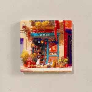 Może przedstawiać: Kwadratowa płytka ceramiczna z kolorową ilustracją sklepu w Stambule. Sklep ma niebieską markizę, a nad wejściem widnieje napis "Istanbul". Kilka kotów siedzi przed sklepem.