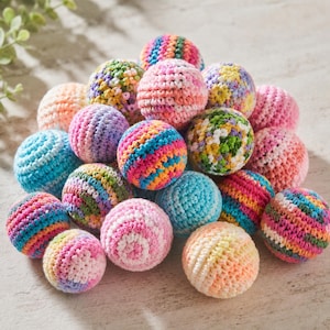 Puede incluir: Una colección de bolas de ganchillo coloridas en varios tamaños y patrones. Las bolas presentan una mezcla de colores vibrantes, incluyendo rosa, azul, amarillo y verde. Las bolas hechas a mano están dispuestas en una pila.
