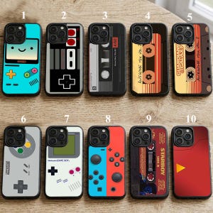 May include: A collection of ten phone cases with various designs. The cases feature retro video game controllers, cassette tapes, and a smiling character. Colors include blue, red, black, gray, and yellow. Some cases have text like "GAME BOY" and "STARBOY SIDE B".