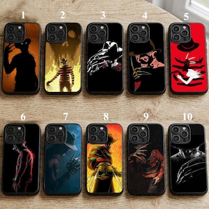 May include: A collection of ten black phone cases featuring various horror-themed designs. The cases showcase images of a character with a hat and bladed glove, in colors like red, black, and orange. Each case has a glossy finish.