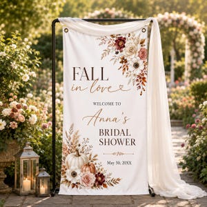 以下が含まれることがあります： FALL in love WELCOME TO Anna's BRIDAL SHOWER May 30, 20XXという文字が書かれた白い縦型バナー。デザインには、白、クリーム色、バーガンディの花、乾燥した草、カボチャを使ったフラワーアレンジメントが上下の角にあしらわれています。