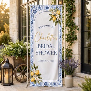 May include: A vertical rectangular banner featuring a white background with a blue and white tile-patterned border. The text reads Welcome to Charlotte's Bridal Shower August 27, 20XX, accented by illustrations of yellow lemons and white blossoms.