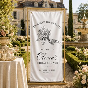 May include: A white vertical banner held by a gold metal frame, featuring a black line art illustration of a skeleton hand holding a floral bouquet. Text reads: 'TIL DEATH DO US PARTY, WELCOME TO Olivia's BRIDAL SHOWER, OCTOBER 18, 20XX, New York, NY.