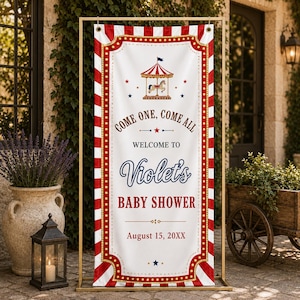 Op de afbeelding: Een verticaal rechthoekig spandoek met een rood-wit gestreepte rand in circusthema. Het witte midden toont een carrouselillustratie, rode en blauwe sterren en de tekst: Come One, Come All, Welcome to Violet's Baby Shower, August 15, 20XX.