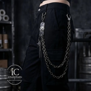 May include: Black cargo pants with a silver chain and a leather accent featuring a skull design. The chain is attached to the pants with a clasp and a hook. The iCharmStudio logo is in the bottom left corner.