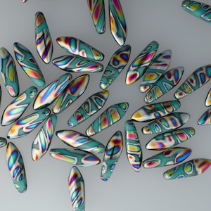 May include: A collection of teal, oval-shaped beads with iridescent, colorful patterns. The beads are scattered across a light gray surface, showcasing a variety of designs and color combinations, including yellow, pink, and blue.