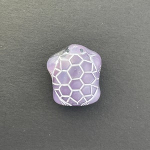 May include: A purple turtle figurine with a white shell and a honeycomb pattern. The turtle is carved from stone and has a smooth, polished finish.