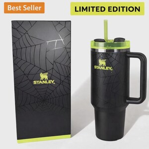 May include: A black Stanley travel mug with a green lid and straw, decorated with a spiderweb pattern. The mug has a handle and the Stanley logo. A matching black box with the same design is next to it. Text reads "Best Seller" and "Limited Edition."