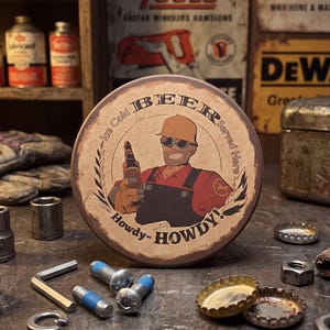 Pode incluir: Uma placa de metal circular com um trabalhador da construção civil em desenho animado, usando capacete e óculos de sol, segurando uma garrafa de cerveja. O texto diz Ice Cold BEER Served Here e Howdy-HOWDY! Acabamento castanho vintage.