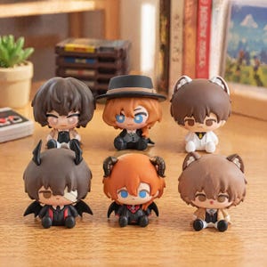 Può includere: Una collezione di sei piccole statuette in stile chibi disposte su due file. Le figure presentano diversi colori di capelli, tra cui marrone e arancione, e vari accessori come un cappello nero, orecchie di animali, corna e piccole ali, tutte con abbigliamento formale.
