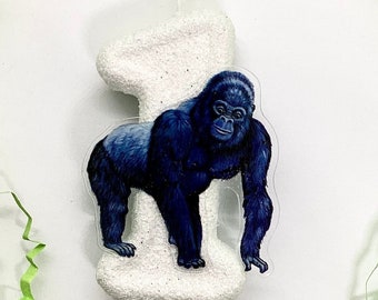 Op de afbeelding: Witte verjaardagskaars in de vorm van het nummer één met een glitterafwerking. Een gorilla-sticker is bevestigd aan de kaars.