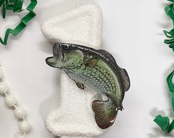 May include: White cake candle shaped like the number one with a green and brown bass fish attached to the side.