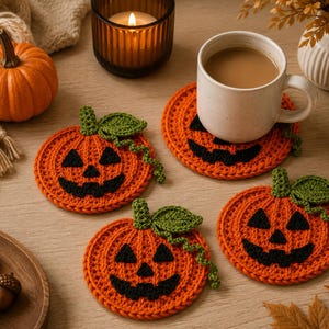 May include: Three round orange crochet coasters shaped like jack-o'-lanterns with black yarn faces, green stems, and curly vines. Each coaster features a textured stitch pattern, and one coaster supports a white ceramic mug filled with coffee.
