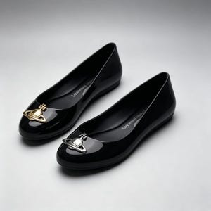 May include: A pair of black glossy ballet flats featuring a rounded toe. Each shoe is adorned with a metallic orb emblem on the front, one in gold tone and the other in silver tone. The interior soles feature white printed branding text.